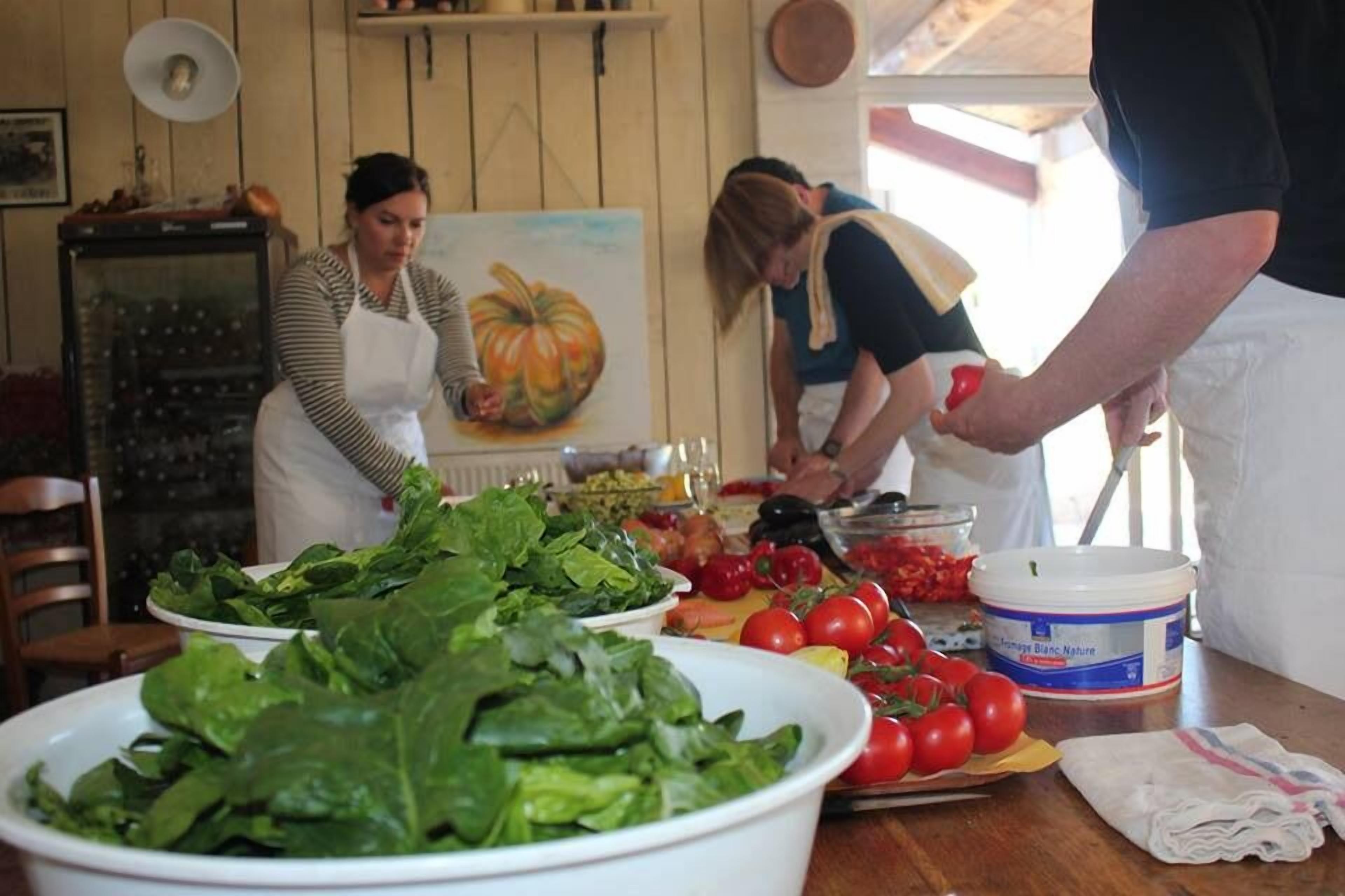 A kitchen with a table full of fresh vegetables, a painting on the wall, and a vintage radio.