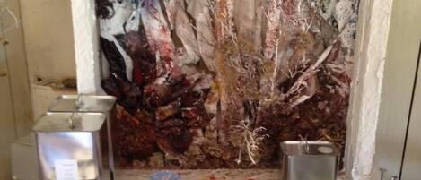 A table with jars of jam, honey, and other condiments, a metal container, and a decorative wall with abstract art.