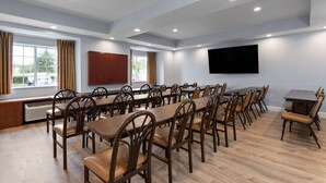 A conference room with long tables and chairs, a large flat-screen TV on the wall, and windows with curtains. - Microtel Inn & Suites by Wyndham Zephyrhills (Zephyrhills)