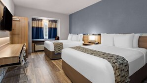 A hotel room with two beds, a desk, a chair, a TV, and a window with curtains. - Microtel Inn & Suites by Wyndham Zephyrhills (Zephyrhills)