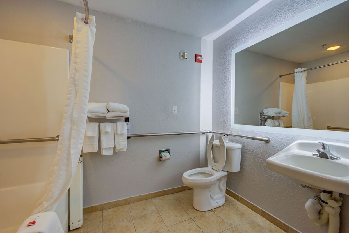 Un baño con inodoro, lavamanos y cortina de ducha.