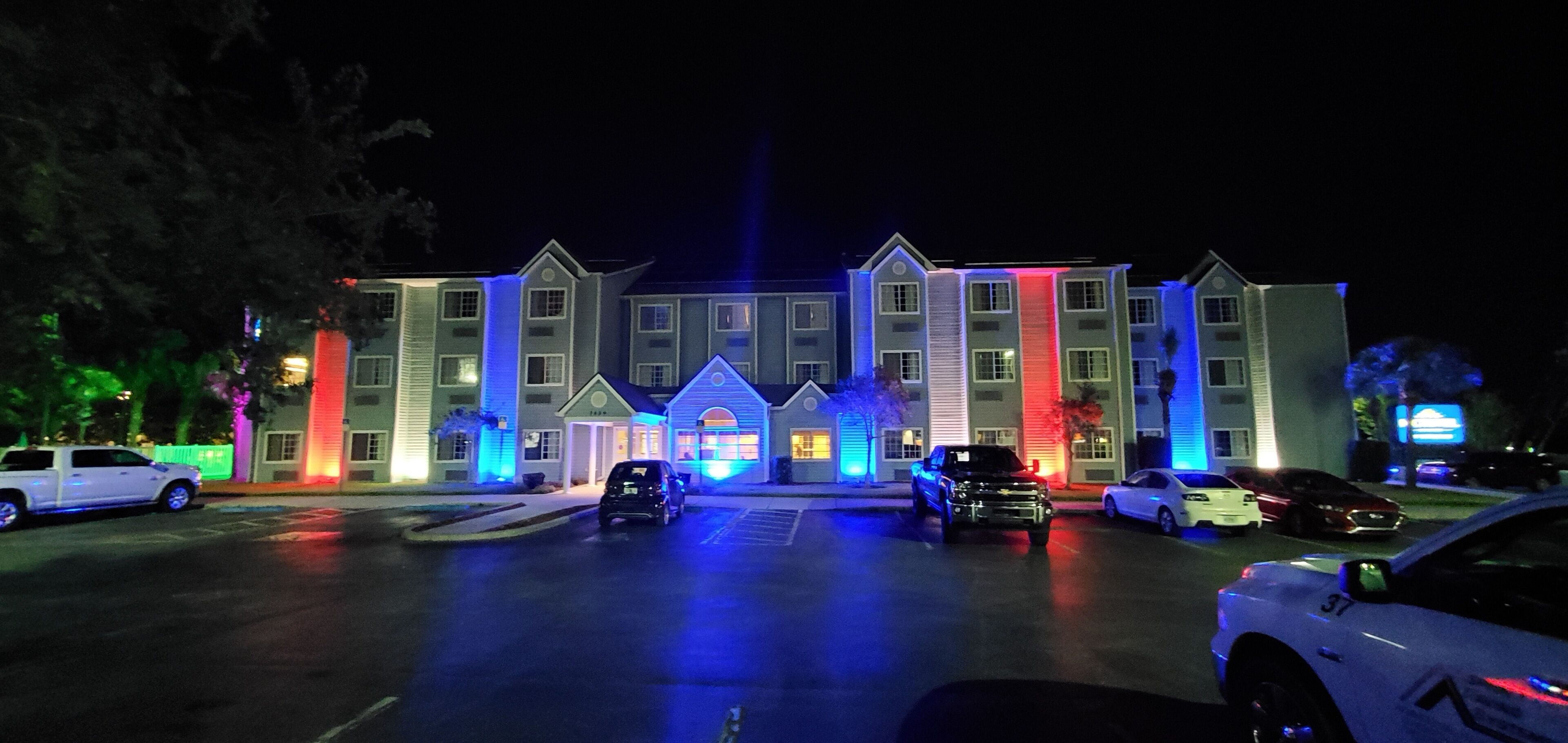 Un hotel de varios pisos con una entrada central y un estacionamiento.