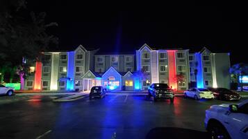 Un hotel de varios pisos con una entrada central y un estacionamiento.
