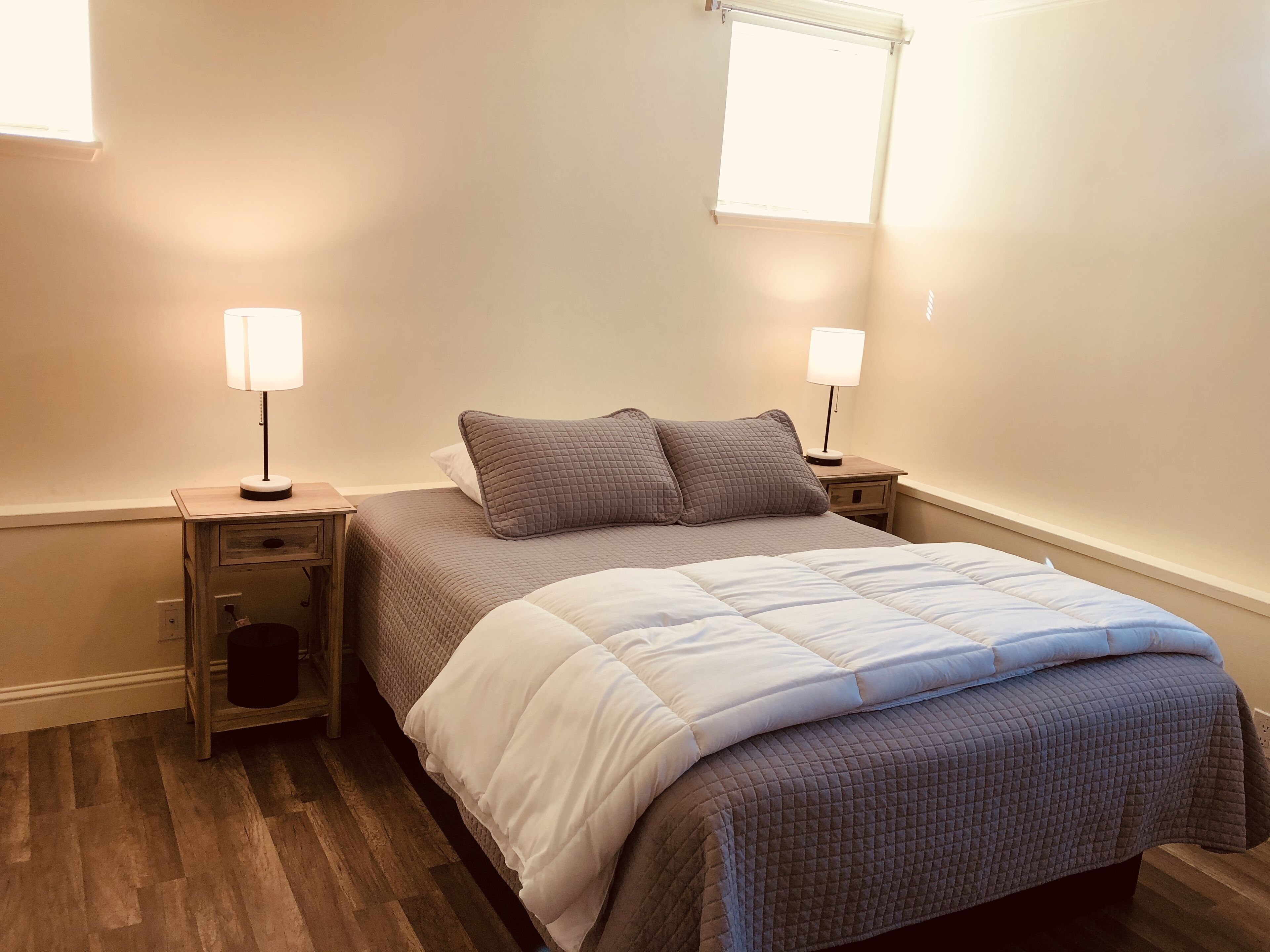 Een slaapkamer met een bed, twee nachtkastjes, een raam en een stopcontact.