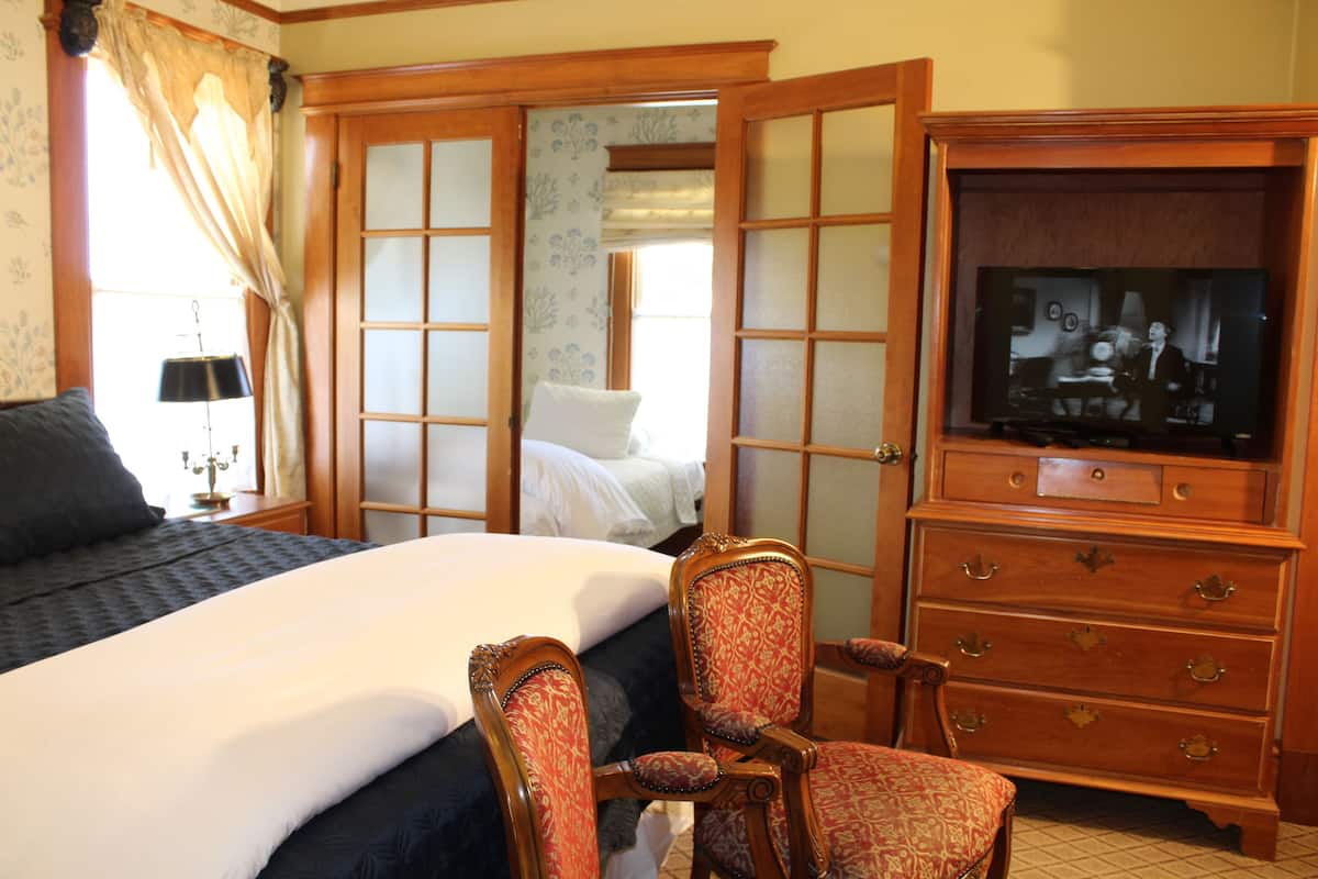 A hotel room with a bed, a chair, a dresser, and a television.