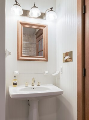 A bathroom with a white sink, a wooden-framed mirror, and two wall-mounted lights.