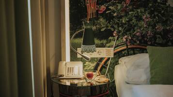 A room with a bed, a bedside table with a lamp, a phone, and a bowl with an apple.
