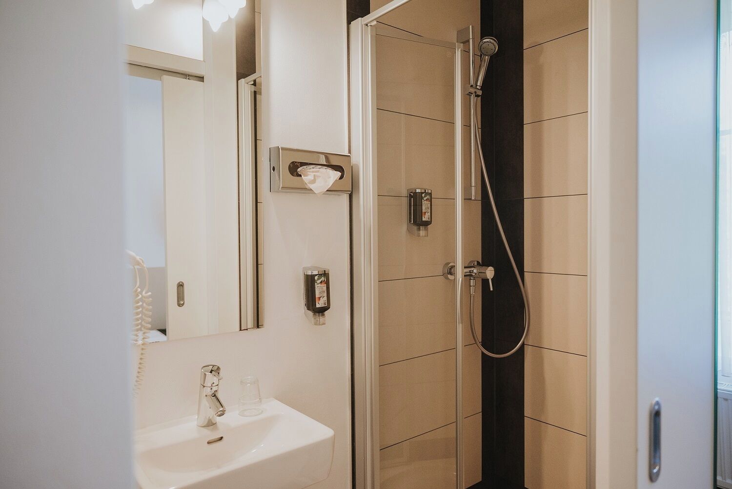 Un baño con lavamanos, espejo y ducha.
