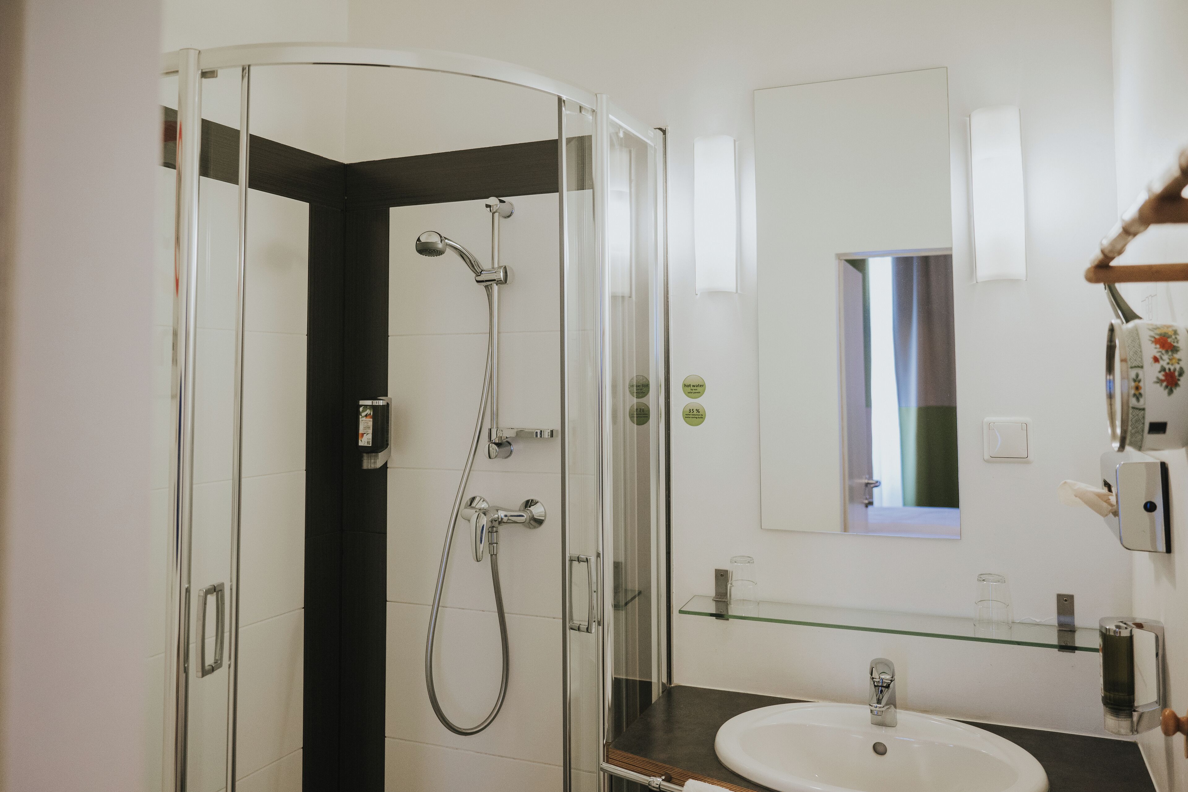 Un baño moderno con cabina de ducha de vidrio, un lavamanos blanco y un espejo sobre él.