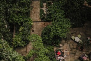 Vista aérea de um pátio com caminhos de pedra, vegetação e áreas de estar ao ar livre.