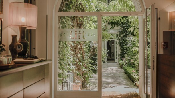 Un umbral que da a un jardín, con un letrero que dice "Bienvenido".
