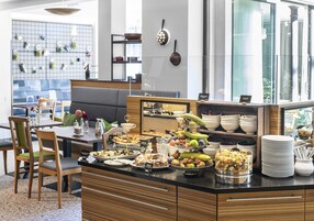 Uma área de buffet com diversos tipos de comida e um espaço de estar com mesas e cadeiras.