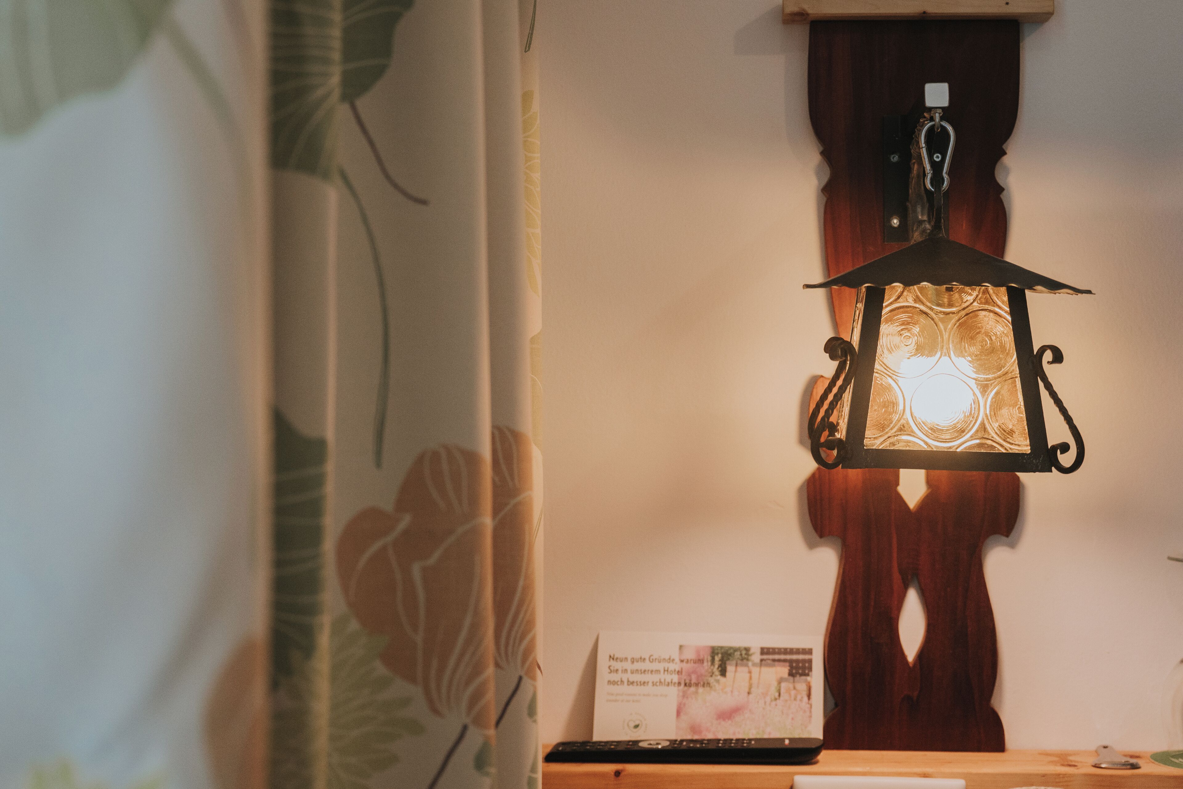 Una habitación con un farol colgante, un aparador de madera y un cartel en la pared.