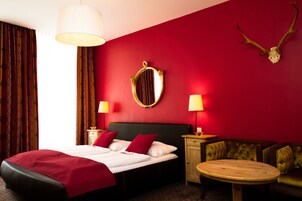 Quarto de hotel com cama, duas mesas de cabeceira, uma mesa redonda e um sofá.