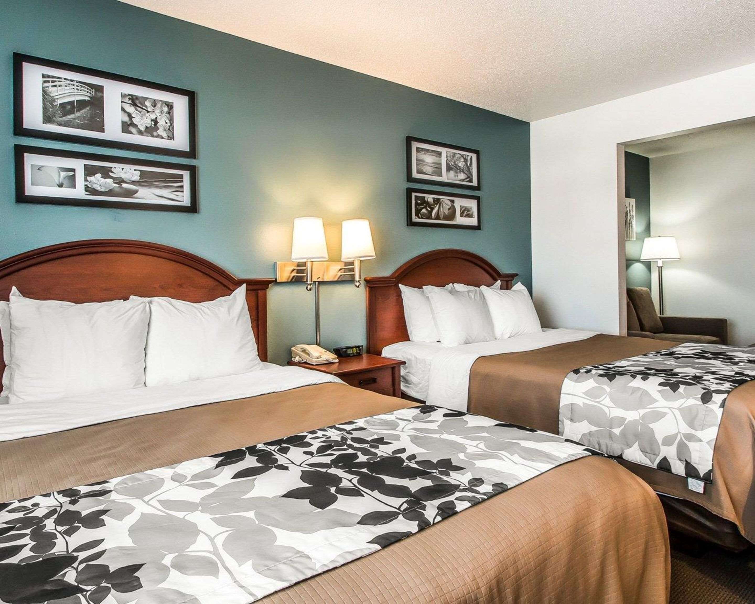 A hotel room with two beds, a nightstand with a lamp, and framed pictures on the wall.