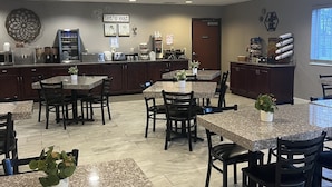 A restaurant with multiple tables and chairs, a kitchen area, and a sign that reads "let's eat".