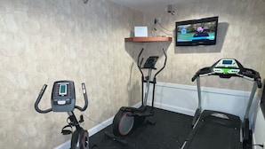 A home gym with an elliptical, a stationary bike, and a treadmill.