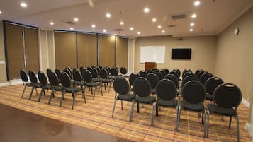 A conference room with rows of chairs, a projector screen, and a carpeted floor.