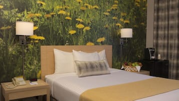 Habitación de hotel con una cama, mesitas de noche, lámparas, un teléfono y una cesta de frutas.
