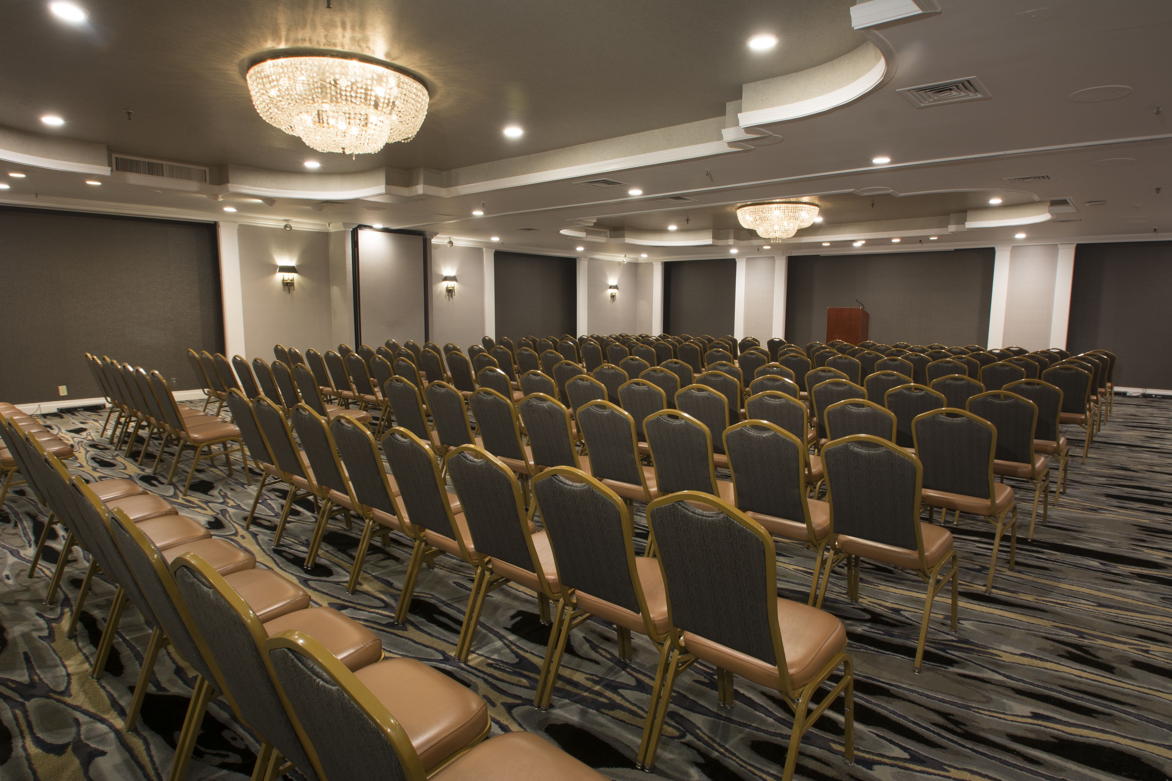 A conference room with rows of chairs, a podium, and a chandelier.