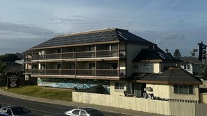 A multi-story building with balconies, solar panels, and a sign for the Ocean Gate Inn. - Ocean Gate Inn (Santa Cruz)