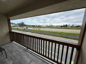 A balcony with a view of a road and greenery.