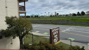 A sign for Ocean Gate Inn, a building with a balcony, and a road with directional arrows. - Ocean Gate Inn (Santa Cruz)