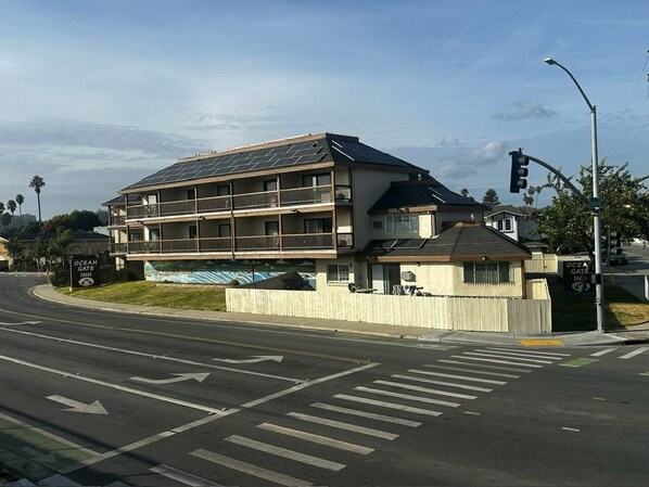 A multi-story building with a flat roof, a balcony on the second floor, and a sign for 'Ocean Gate Inn'.