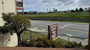 A sign for Ocean Gate Inn, a building with a balcony, and a road with directional arrows. - Ocean Gate Inn (Santa Cruz)