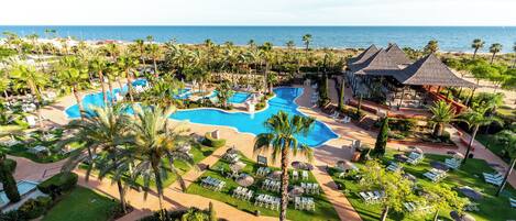 A resort with multiple swimming pools, palm trees, and lounge areas.
