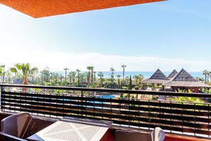 Un balcón con vistas a una piscina, palmeras y edificios de un complejo turístico.