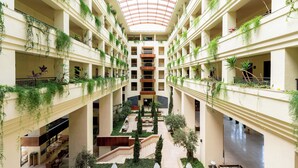 A multi-level atrium with a central staircase, balconies with greenery, and seating areas.