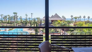 A resort view with a pool, palm trees, and a beach.