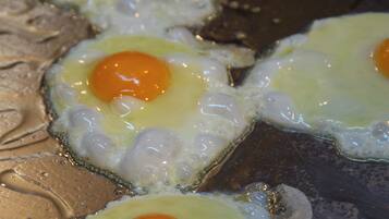 Cuatro huevos fritos sobre una superficie metálica.
