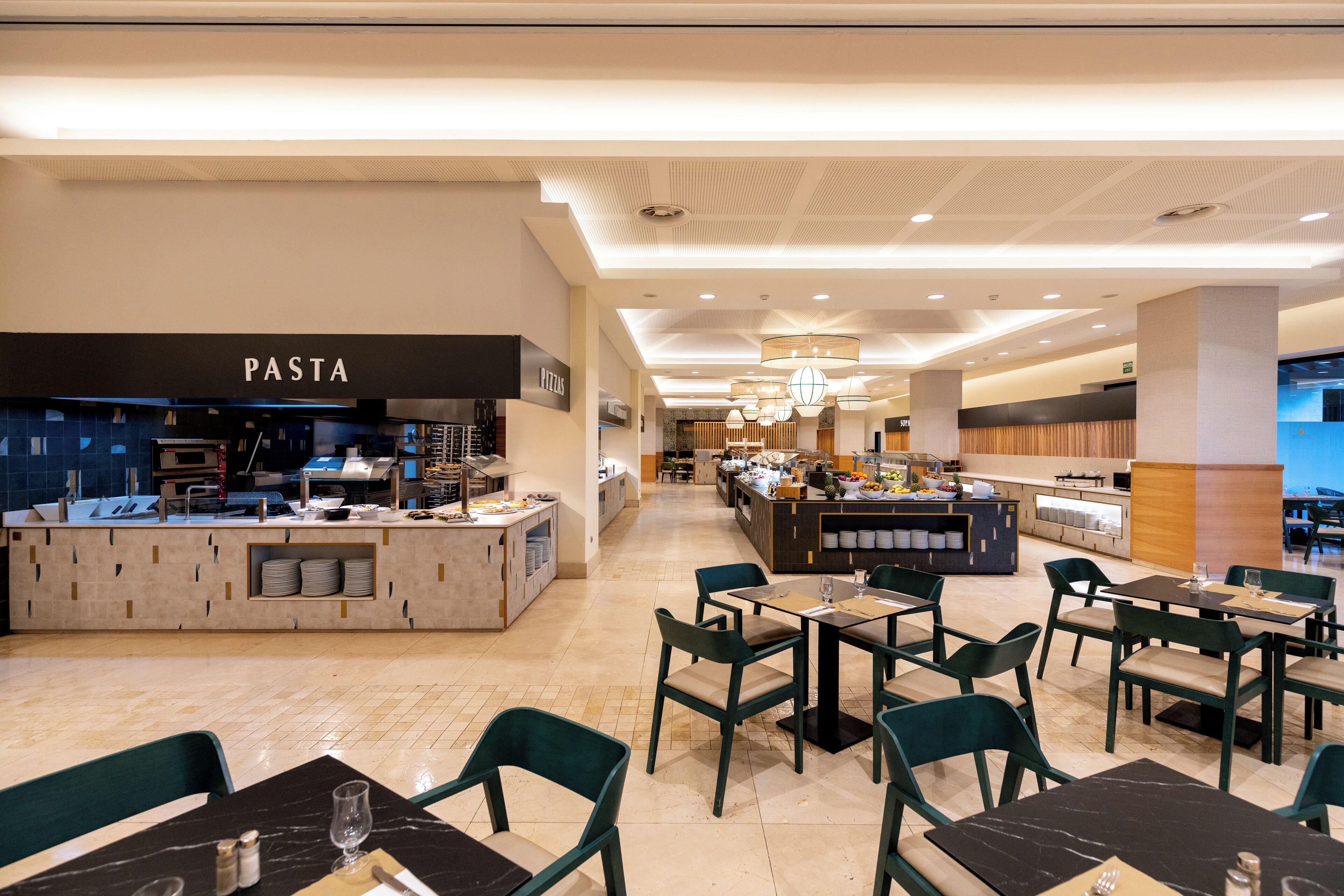 A modern restaurant with a pasta station, multiple dining areas, and a bar.