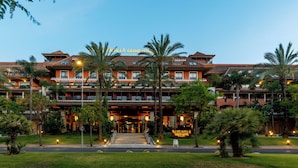 A large, multi-story hotel with a traditional architectural style, featuring a prominent entrance with steps and a covered walkway.