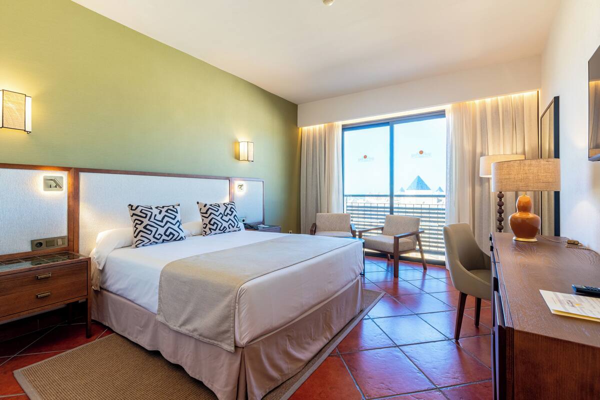 Een hotelkamer met een bed, bureau, stoelen en uitzicht.