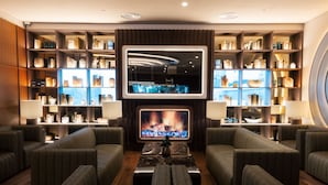 A modern lounge area with sofas, a fireplace, and a large bookshelf.