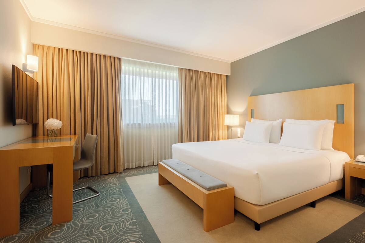 Ein Hotelzimmer mit einem großen Bett, einem Schreibtisch, einem Sessel und einer Bank.