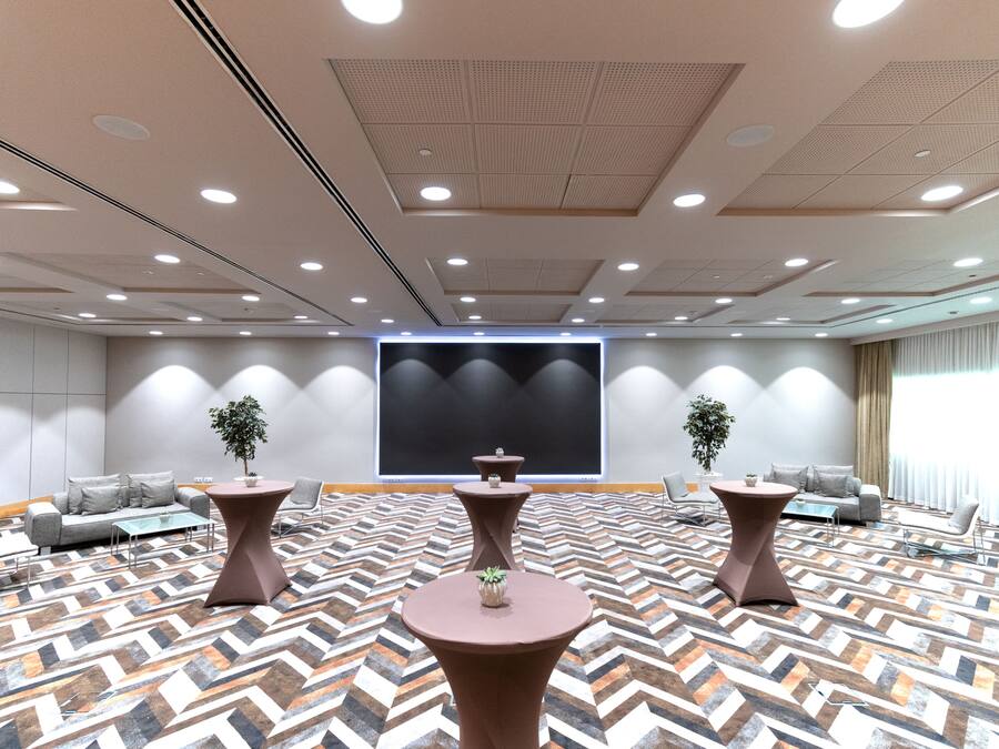 A conference room with a large screen, multiple tables, and sofas arranged for meetings.