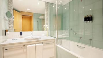 Un baño moderno con ducha envuelta en vidrio, un lavabo blanco y un espejo grande.
