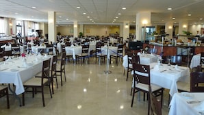 A spacious dining area with multiple tables set for service, a kitchen area in the background, and a clean, well-lit environment. - Globales Los Patos Park (Benalmádena)