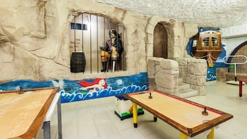 Une pièce décorée d’une fresque représentant une sirène, avec un coffre en bois et une statue de pirate derrière des barreaux.