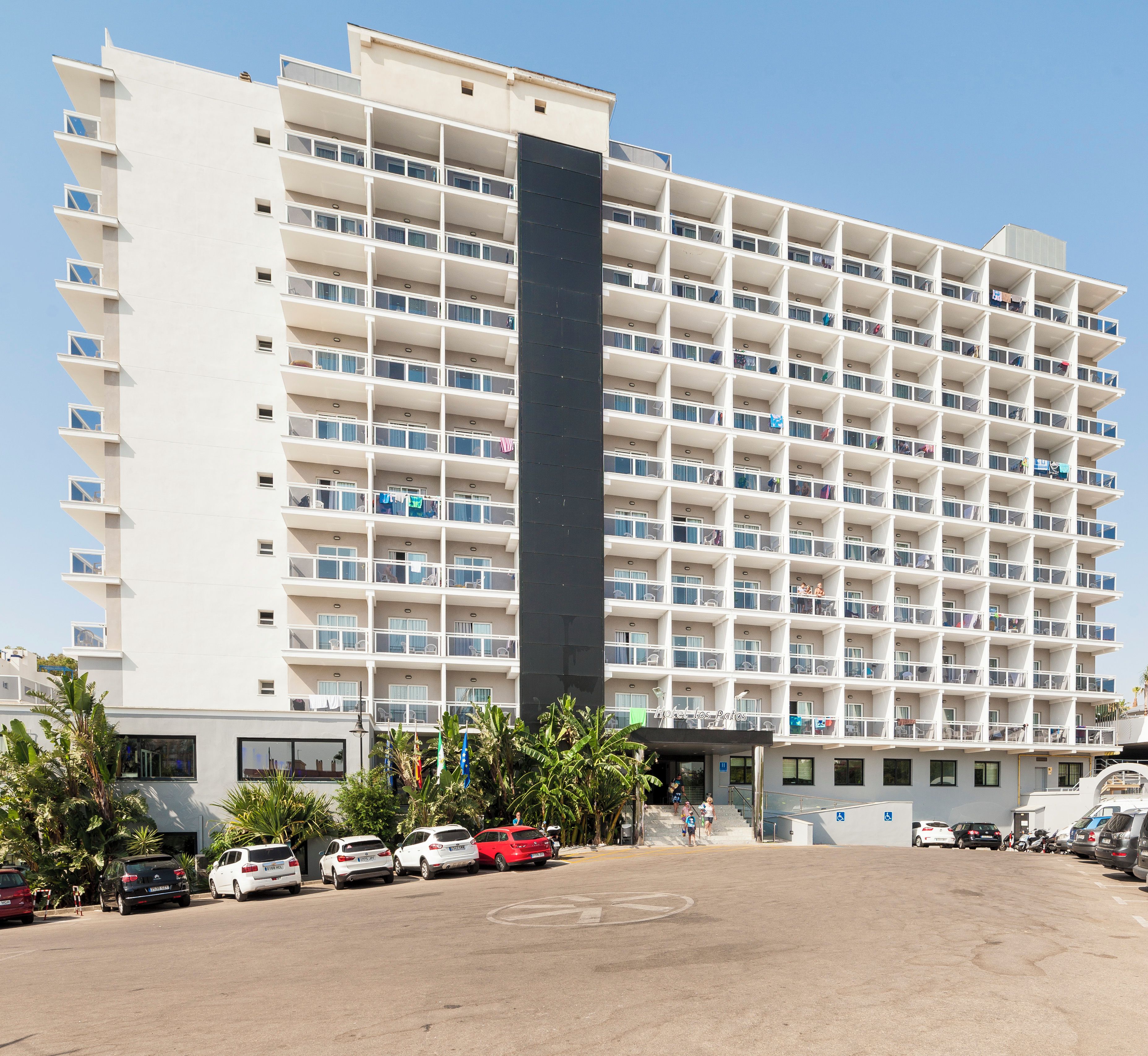 Un hotel a più piani con una torre centrale, balconi e un'area di parcheggio.