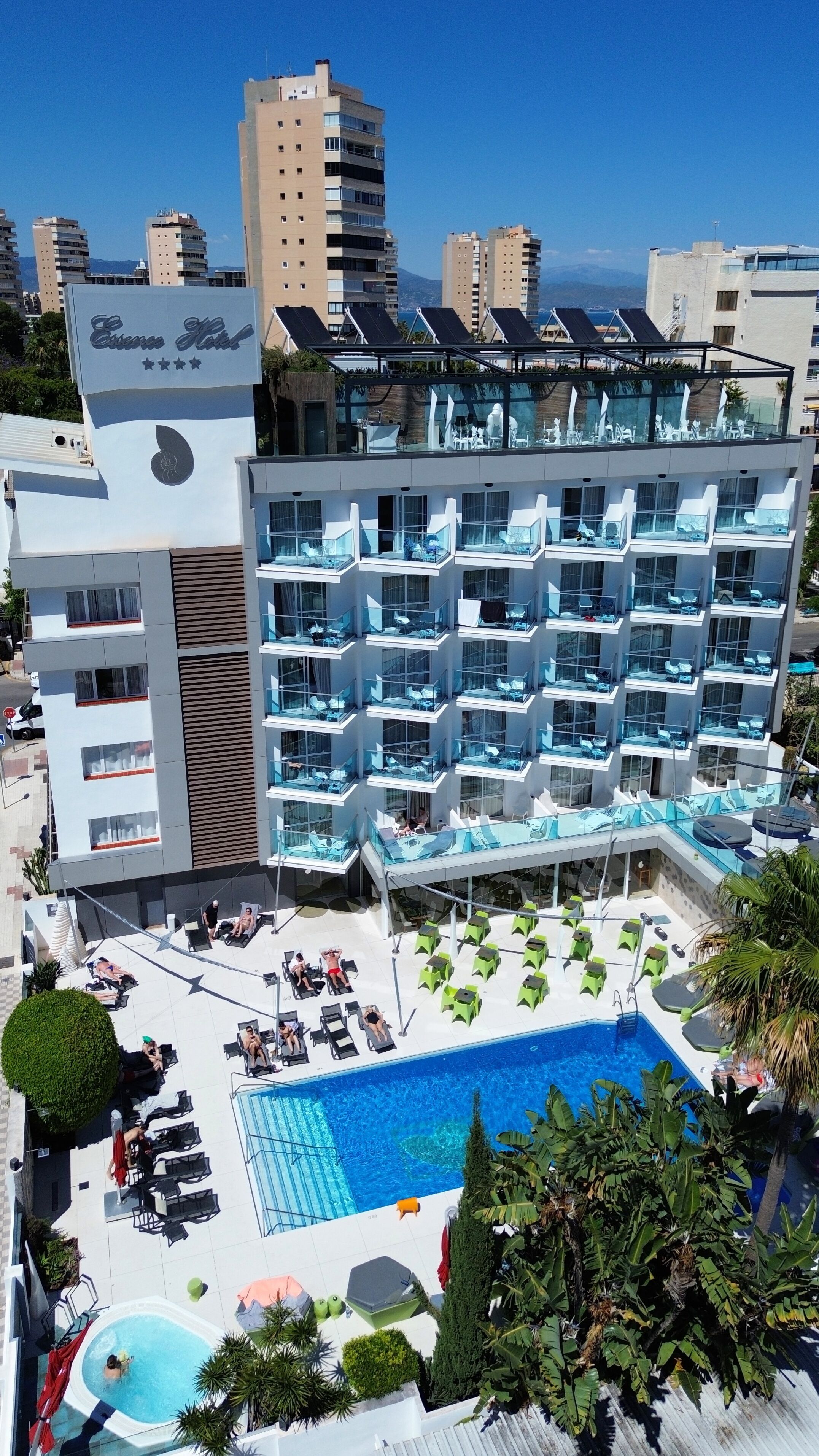 Un hôtel doté de nombreux balcons, d’une piscine et d’une terrasse sur le toit équipée de panneaux solaires.