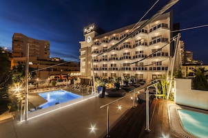 Een hotel met een zwembad, buitenterras en een goed verlicht balkon.