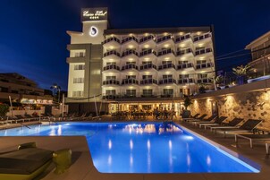 Un hotel con piscina, zona de estar al aire libre y fachada bien iluminada.