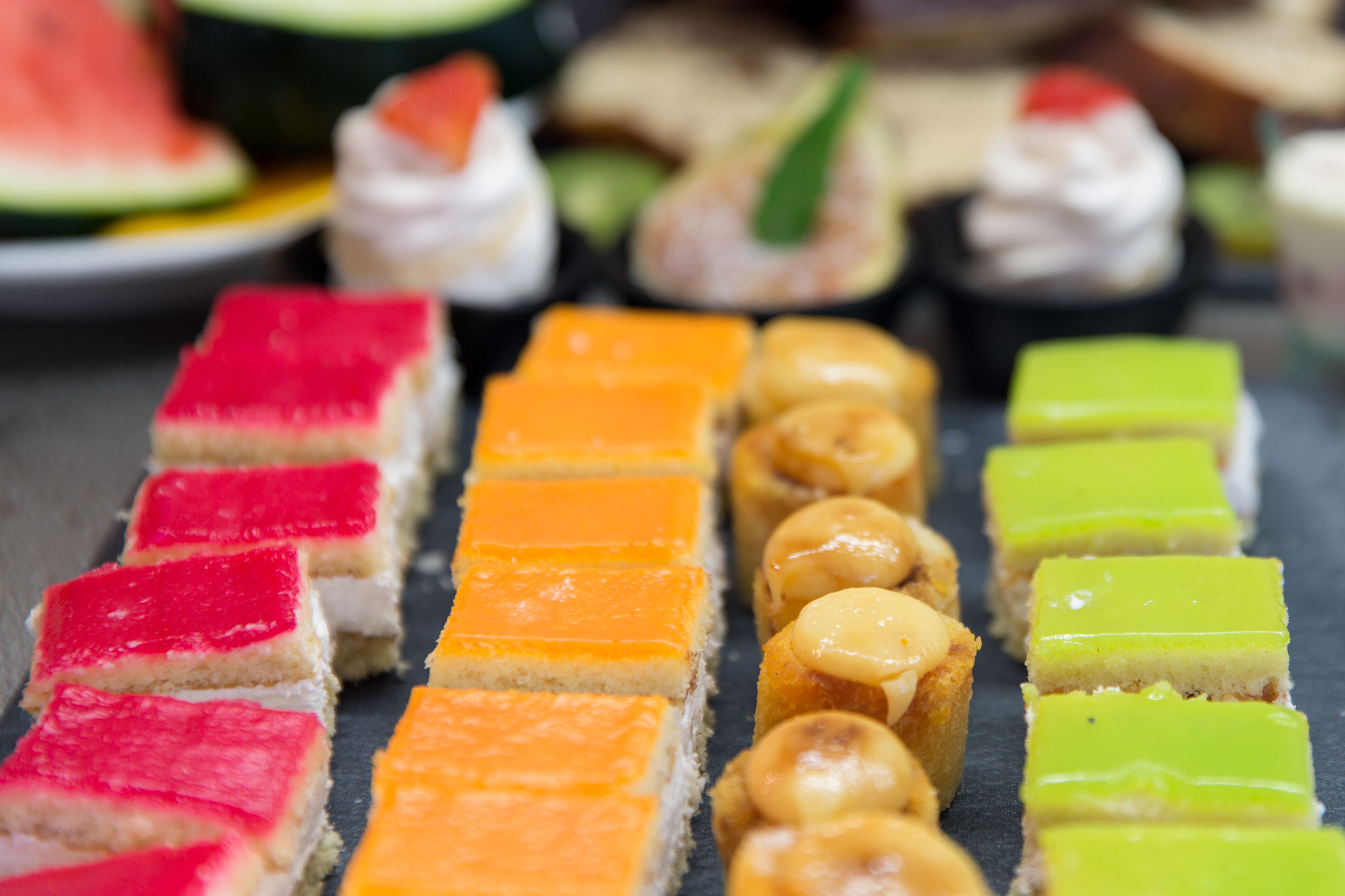 Verschillende kleurrijke desserts gerangschikt op een leistenen dienblad.