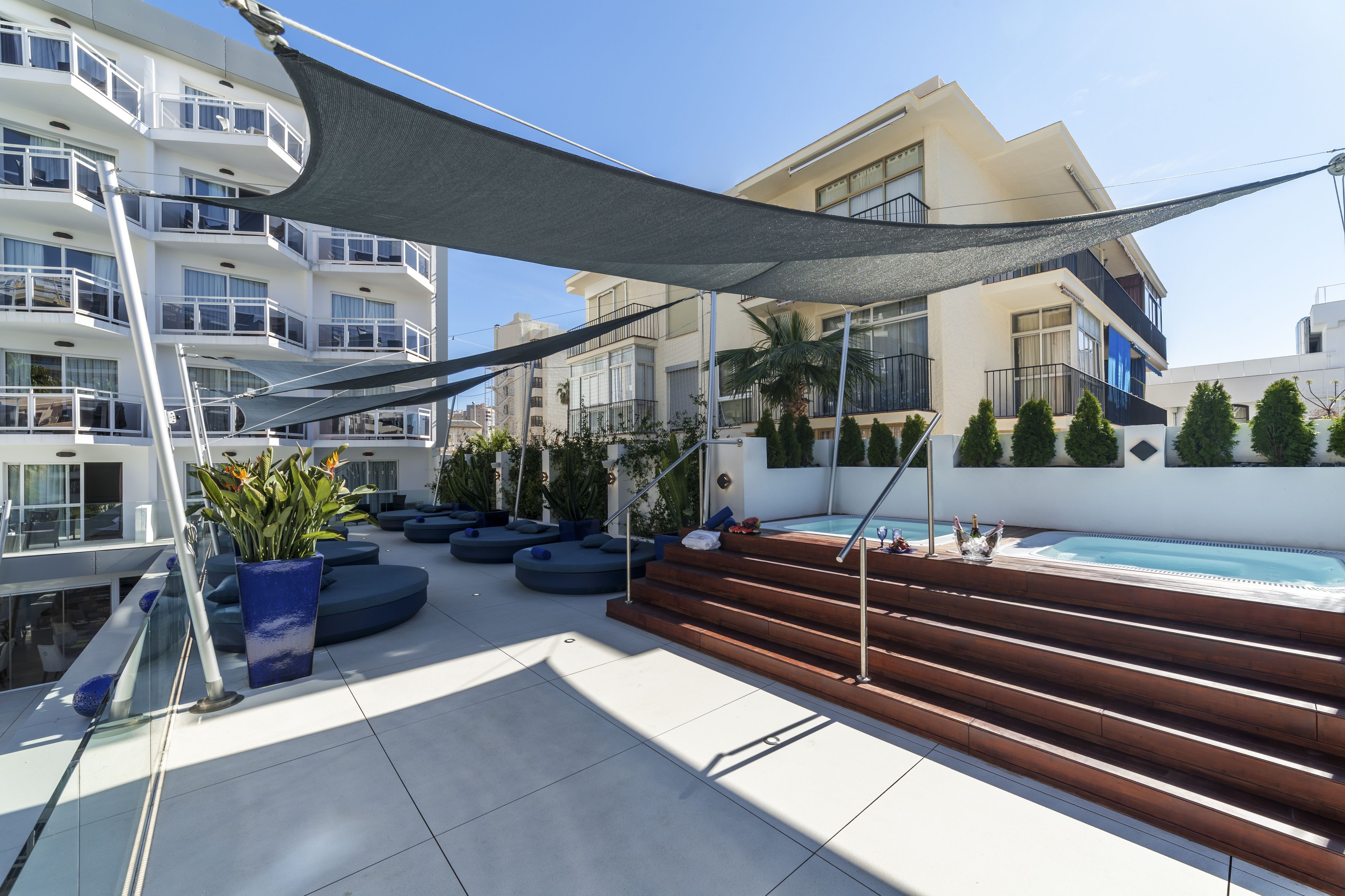 Une terrasse sur le toit avec une piscine, des sièges extérieurs et un escalier menant à un balcon.