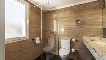 Une salle de bain moderne dotée d’une douche à parois de verre, de toilettes et d’un lavabo en marbre.